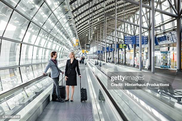 business travellers on man conveyor at airport - business traveler stock pictures, royalty-free photos & images