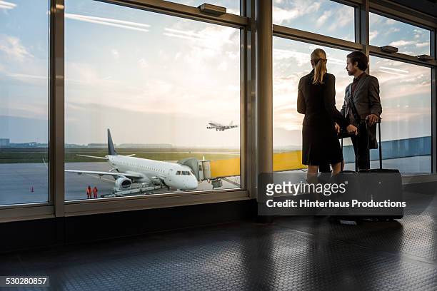 two business travellers staning at airport window - flughafen stock-fotos und bilder