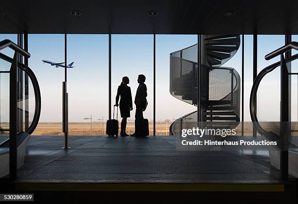 silhouette business travellers at airport - airport indoor stockfoto's en -beelden