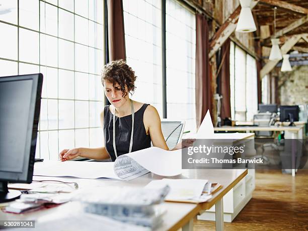 female architect reviewing project plans at desk - architecte plan stockfoto's en -beelden