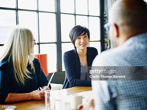 businesswoman leading discussion with colleagues - leanincollection stockfoto's en -beelden