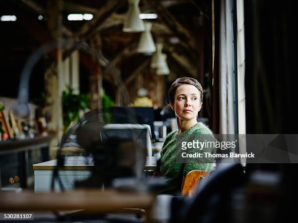 businesswoman at workstation looking out window - leanincollection foto e immagini stock