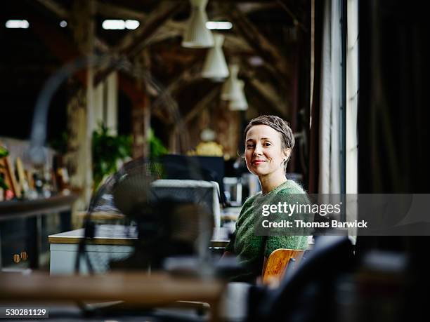 smiling businesswoman sitting at workstation - capacidades diferentes fotografías e imágenes de stock