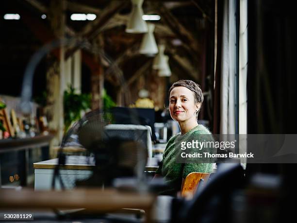 smiling businesswoman sitting at workstation - portretfoto stockfoto's en -beelden