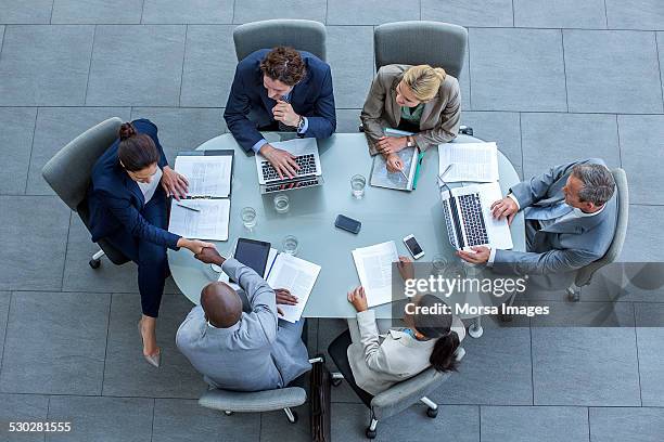 businesspeople shaking hands at conference table - vlak erboven tafel stockfoto's en -beelden