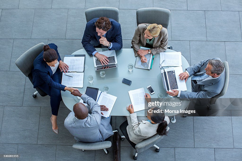 Businesspeople shaking hands at conference table