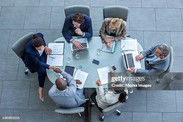 businesspeople shaking hands at conference table - conference table stock pictures, royalty-free photos & images