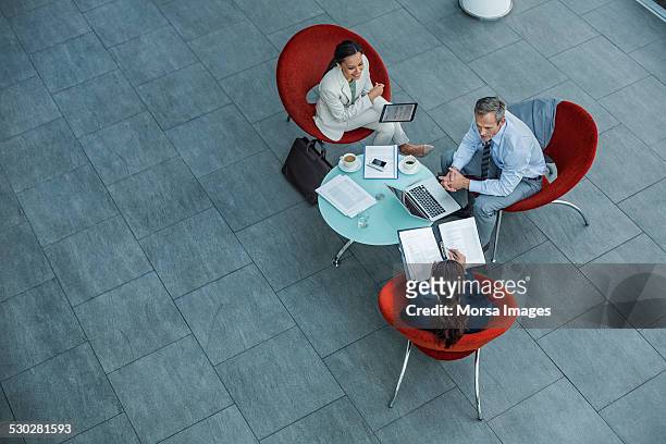 businesspeople discussing strategy at coffee table - elevated view stock-fotos und bilder