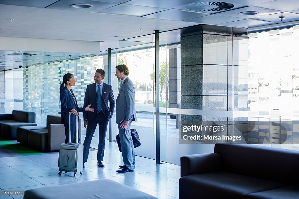 Businesspeople with luggage discussing at lobby