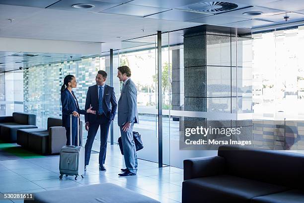 businesspeople with luggage discussing at lobby - voyage d'affaires photos et images de collection