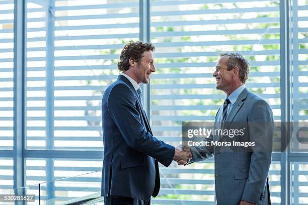 businessmen shaking hands in office - handshake business zwei personen stock-fotos und bilder