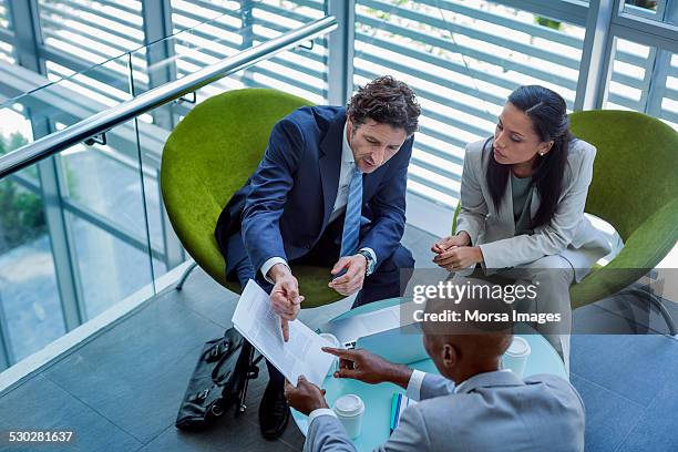 businesspeople discussing over documents in office - abbigliamento da lavoro formale foto e immagini stock