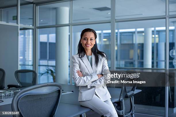 happy businesswoman sitting arms crossed in office - pant suit stockfoto's en -beelden