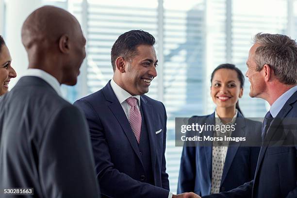businesspeople shaking hands in office - international conference stock pictures, royalty-free photos & images