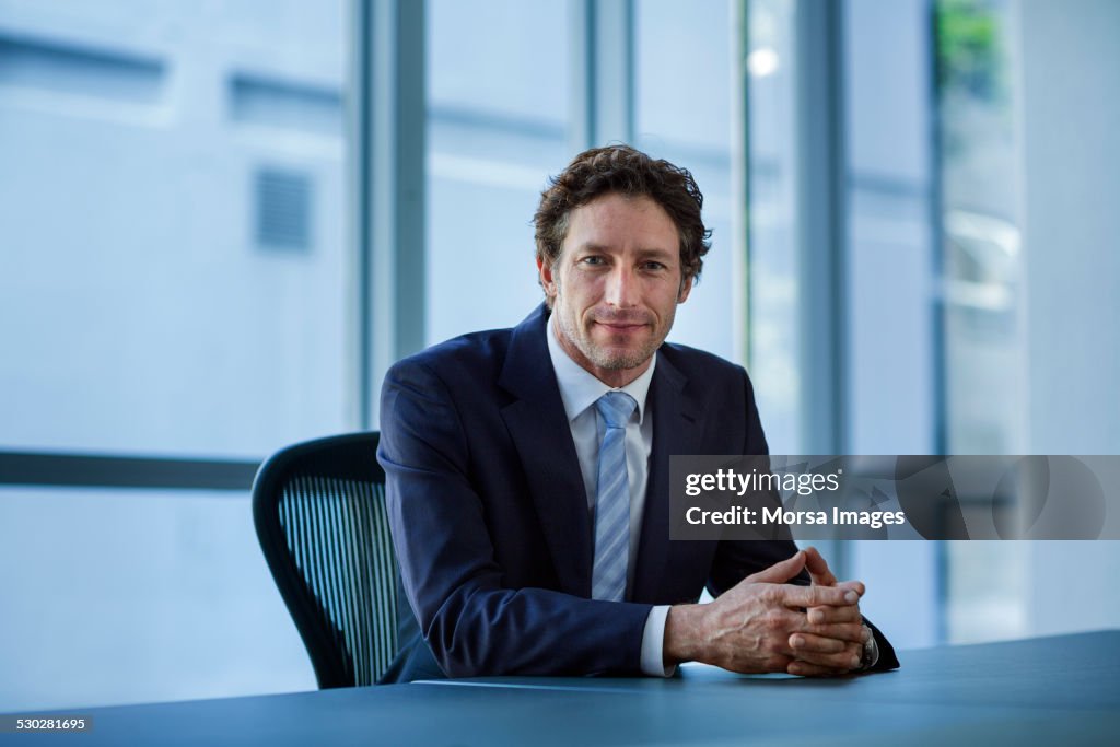 Confident businessman sitting at conference table