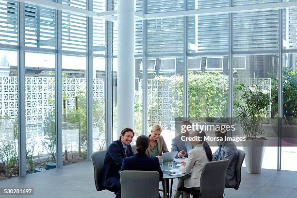 businesspeople discussing at conference table - gray suit stock-fotos und bilder