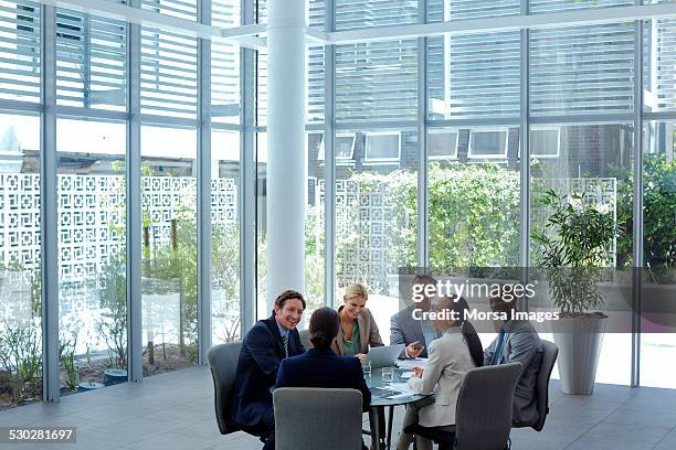 businesspeople discussing at conference table - traje completo fotografías e imágenes de stock