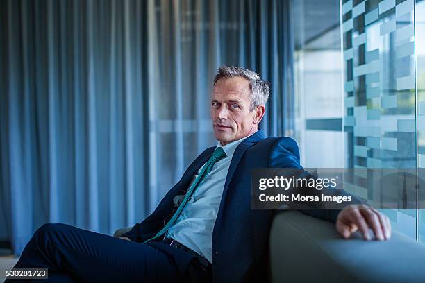businessman relaxing on sofa in office lobby - completo blu foto e immagini stock