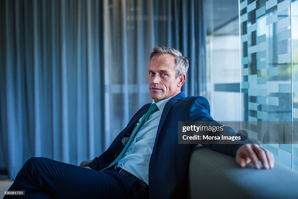 Businessman relaxing on sofa in office lobby