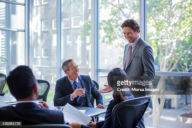 happy businesspeople talking in board room - meeting candid office suit stock-fotos und bilder