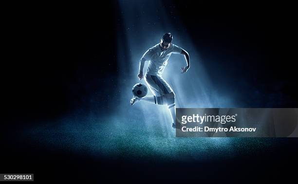 giocatore di calcio calciare la palla in spotlight - calciare foto e immagini stock