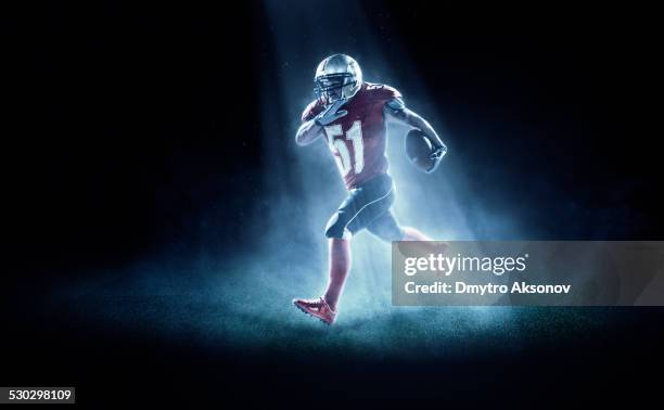 american football player in spotlight - football player tackle stock pictures, royalty-free photos & images