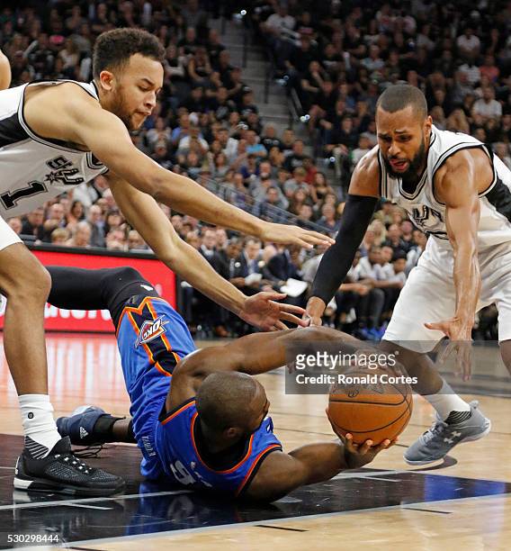 Serge Ibaka of the Oklahoma City Thunder tries to get off a pass from the floor as he is trapped by Kyle Anderson and Patty Mills of the San Antonio...
