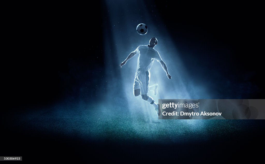 Soccer player kicking ball in spotlight