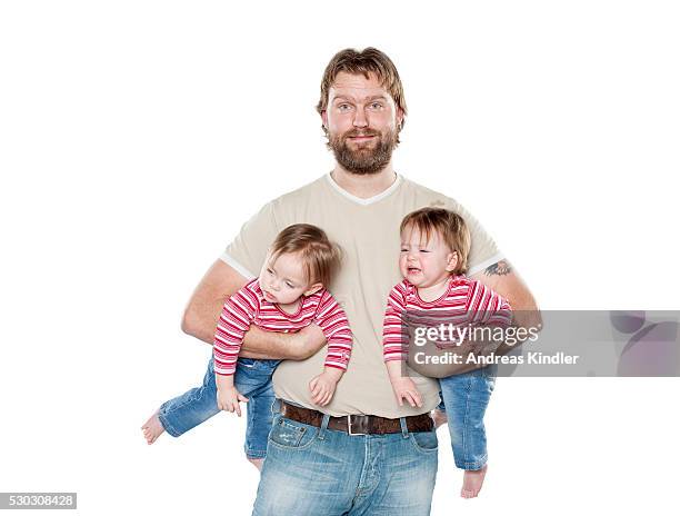 studio portrait of father holding two baby daughters - twin babies stockfoto's en -beelden