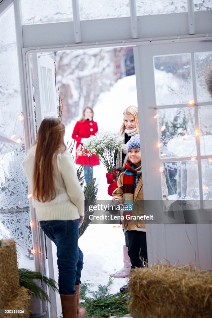 Girl answering door to guests with flowers in snow