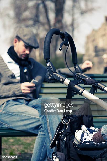 man sitting on bench in park next to baby carriage - man sleeping with cap stock pictures, royalty-free photos & images
