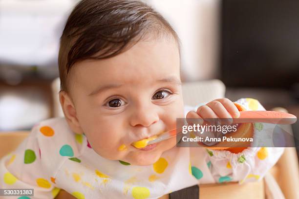 baby boy eating pureed food - alleen babys stockfoto's en -beelden