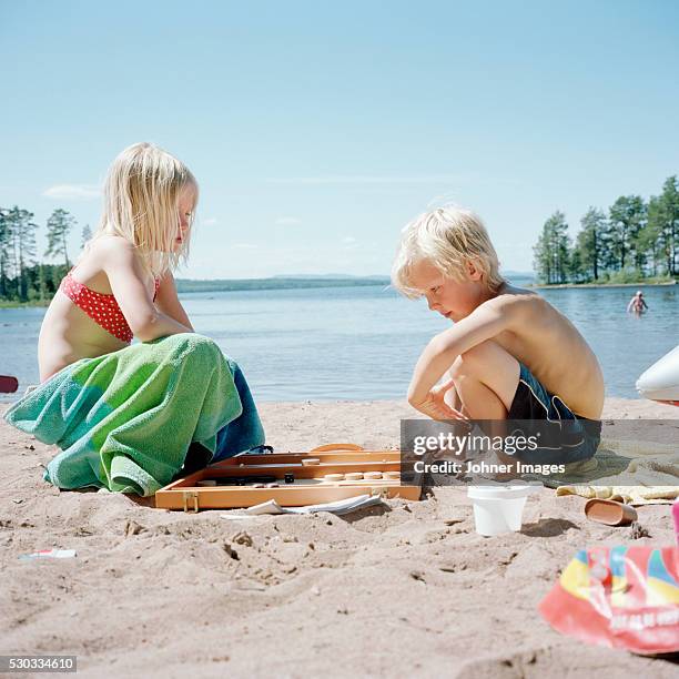 boy and girl playing on beach - bordspel stockfoto's en -beelden