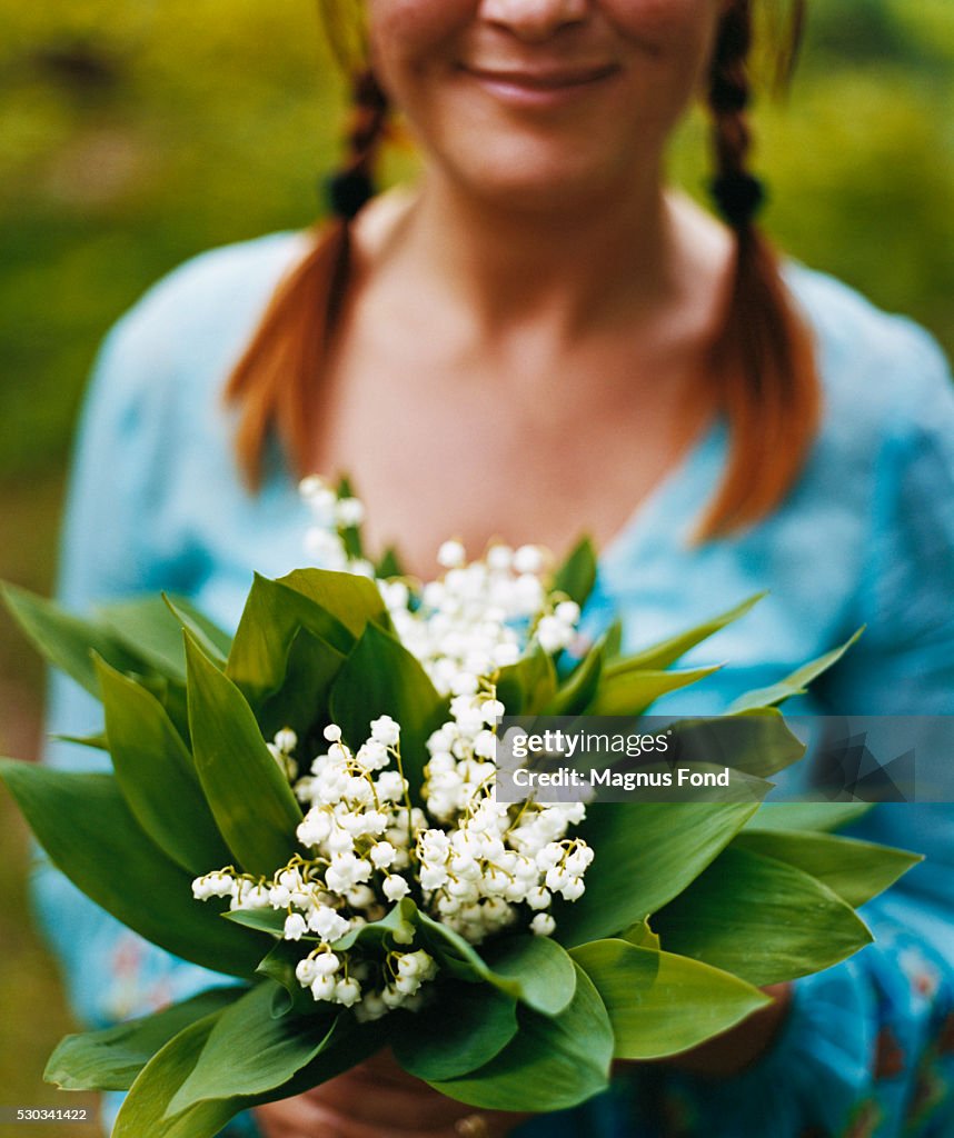 Young woman holding bunch of Lilies of the Valley