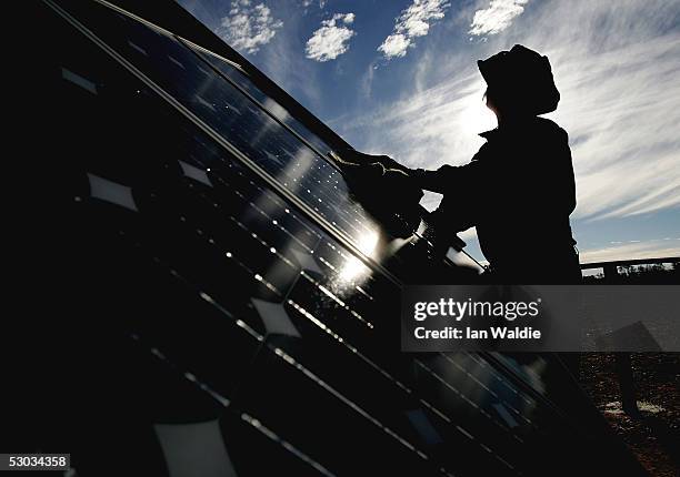 Stockman Gordon Litchfield from Wilpoorinna sheep and cattle station wipes dust from solar cells which power water pumps on his property June 7, 2005...