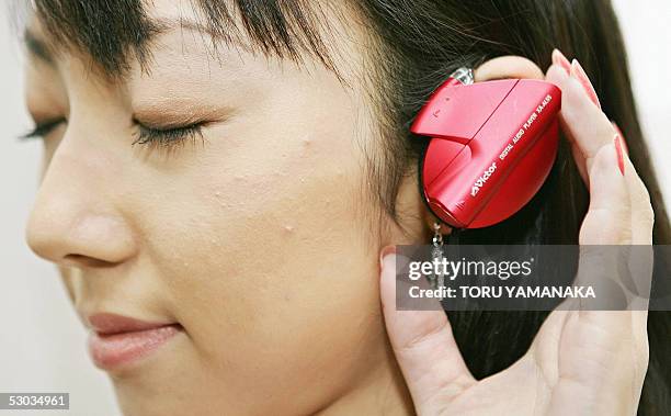 Model of Japan's Victor Compamy shows off the earphone-type digital audio player "XA-AL55" equipped with a 256 megabyte built-in memory at its...