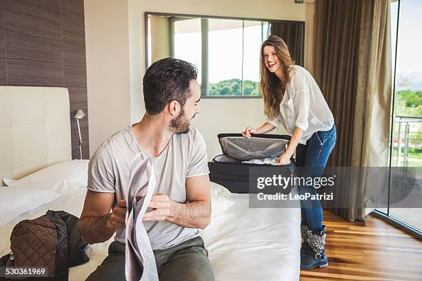 couple in hotel room getting dressed - suitcase couple stockfoto's en -beelden