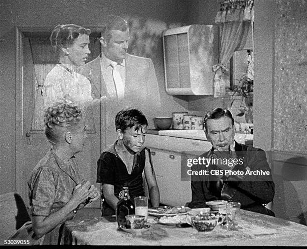 In a scene from the television series 'Topper,' British Leo G. Carroll thinks at the kitchen table as he his watched by an unidentifed woman and boy...