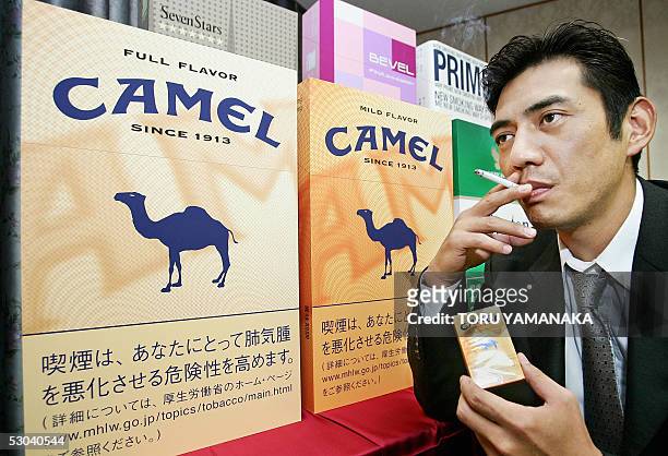 Tsuyoshi Miyashita, employee of Japan Tabacco Inc. , smokes beside big cigarette packages for a sales campaign before a press conference in Tokyo, 09...