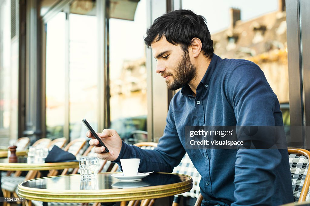 Junger Mann durch soziale Medien in einem Straßencafé