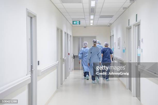 vista trasera de cirujanos caminar por la zona de hospital usando scrubs - doctor hospital fotografías e imágenes de stock