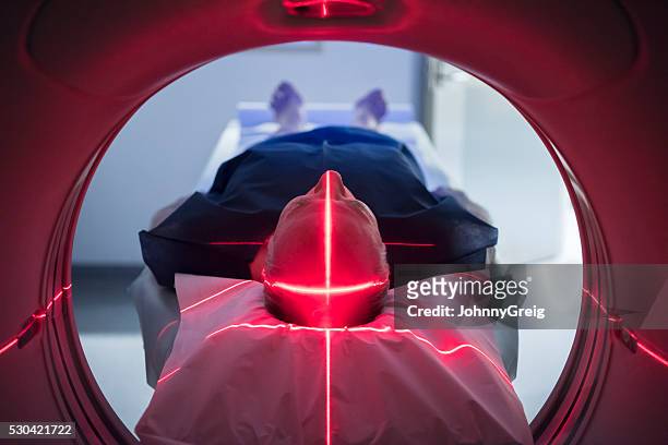 male patient in medical scanner with red lights - medical laser stockfoto's en -beelden