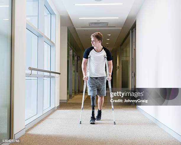 young man with prosthetic leg on crutches - crutch stock pictures, royalty-free photos & images