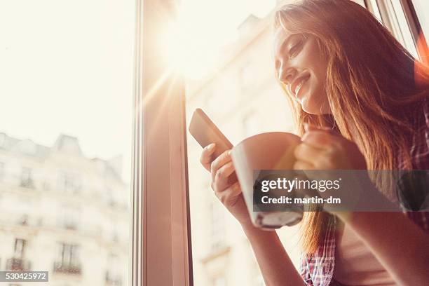 mujer feliz con taza de café en la ventana abierta sms - coffee cup light fotografías e imágenes de stock