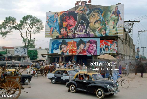 Street scene in Islamabad, Pakistan showing rickshaws, an old two-tone Morris Minor car and the local cinema advertising films often described as...