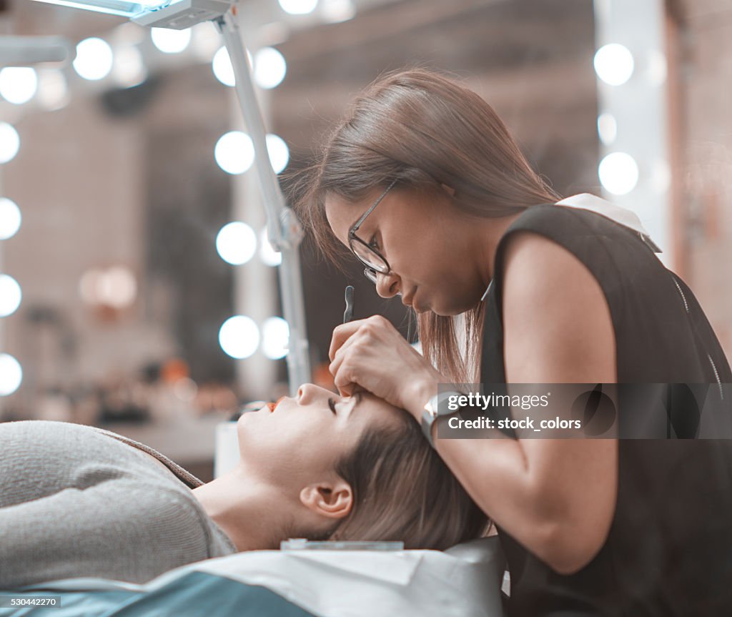 Beautician applying false eyelashes at salon