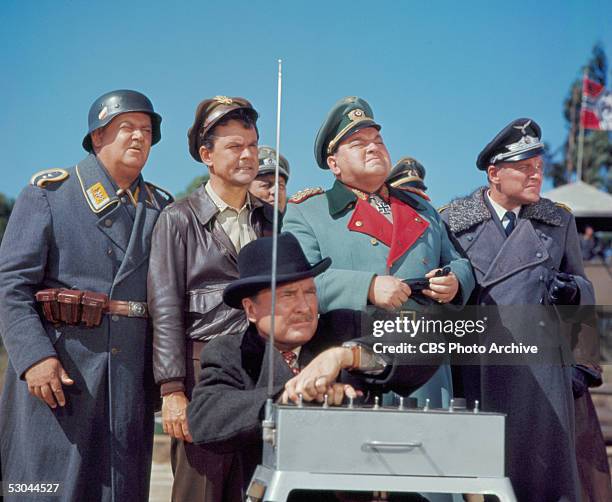 Cast members gaze into the distance as they watch a remote bomb detonation on an episode of the television comedy series 'Hogan's Heroes' called...