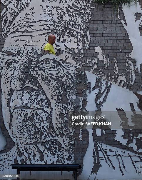 Man walks behind an image of Unionist and activist Jack Mundey by Portuguese artist VHILS on the wall at the Rocks, an historical area of central...