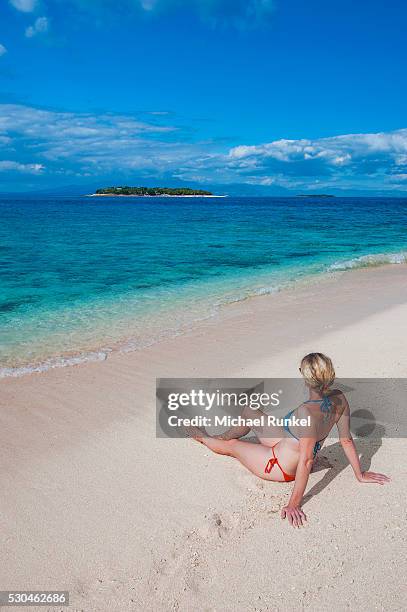 woman sitting on a the white sand beach of beachcomber island, mamanucas islands, fiji, south pacific, pacific - beachcomber island stock pictures, royalty-free photos & images