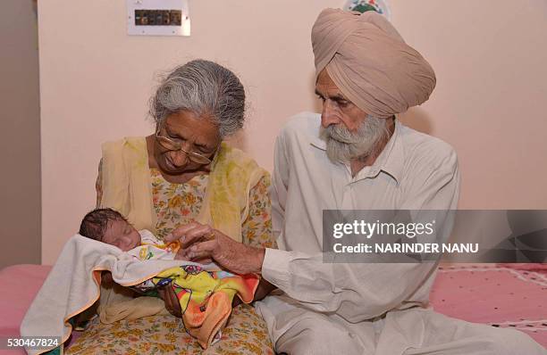 Indian father Mohinder Singh Gill and his wife Daljinder Kaur pose for a photograph as they hold their newborn baby boy Arman at their home in...